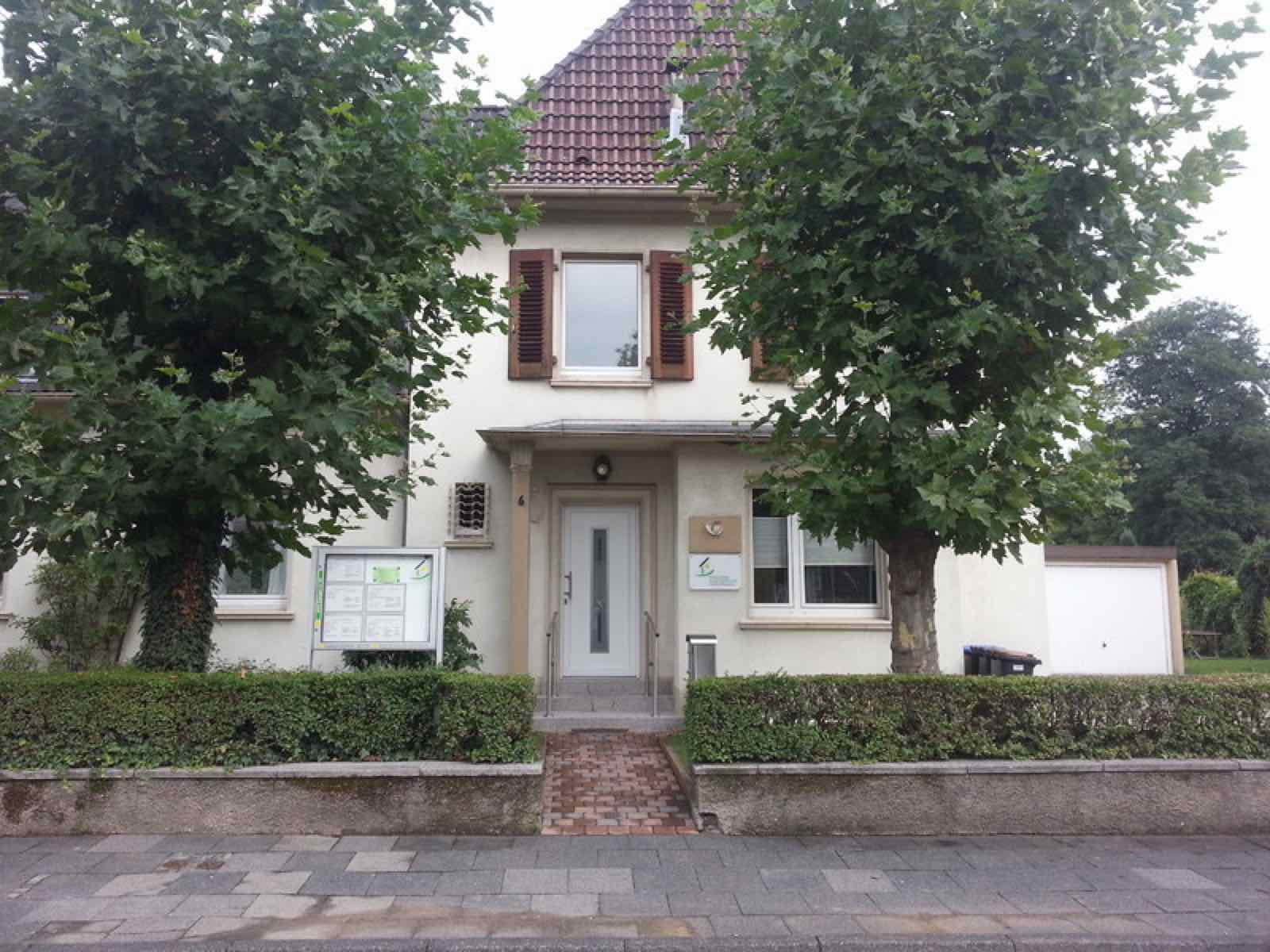 Eingang der Geschäftsstelle Im Sandweg 6 mit Hecke und zwei Platanen