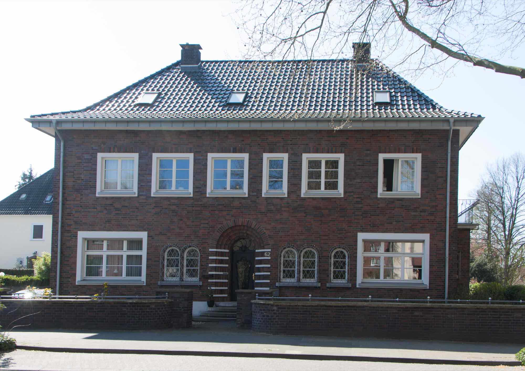 Zweigeschossiges Klinkerhaus mit Walmdach, Sprossenfenstern und Rundbogeneingang