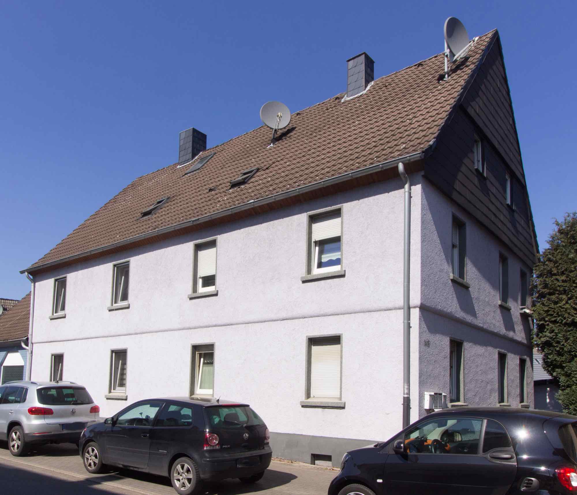 Verputztes Mehrfamilienhaus mit Satteldach in einer Bergarbeitersiedlung bei Sonnenschein