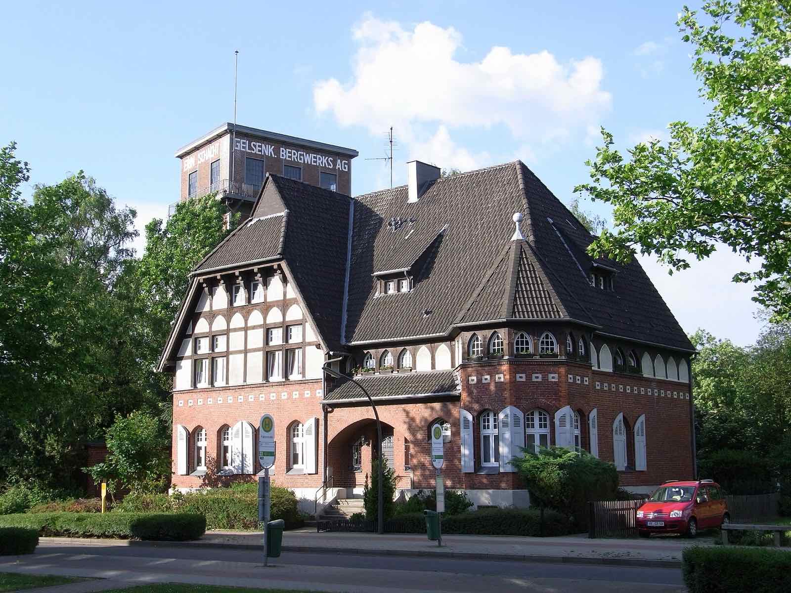 Backsteinhaus mit Fachwerkgiebel vor dem Förderturm der Zeche Erin